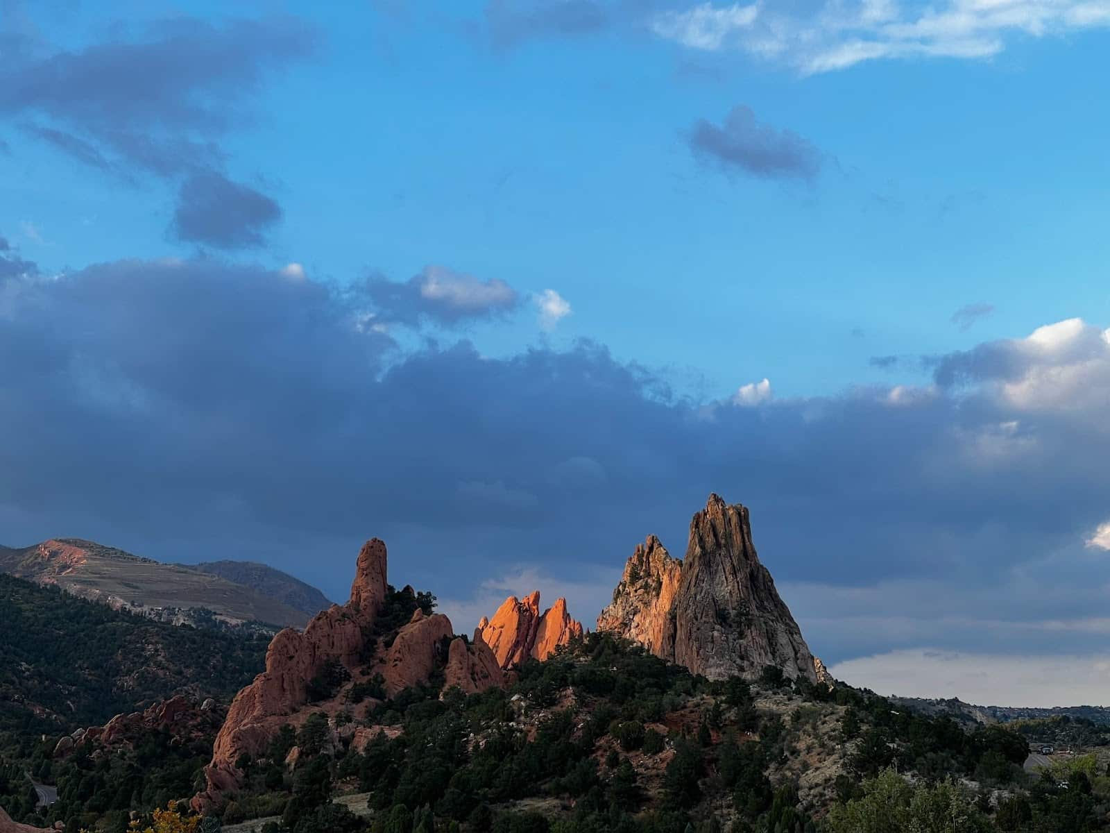 A rock range in Garden of the Gods in Colorado Springs, CO., beneath a blue sky filled with clouds