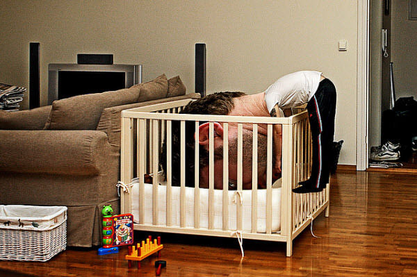 A man relaxing with his oversized head in a playpen